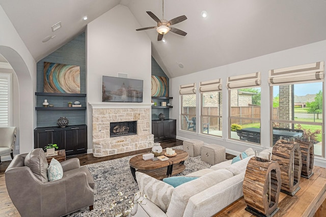 living area featuring a healthy amount of sunlight, high vaulted ceiling, ceiling fan, and wood finished floors