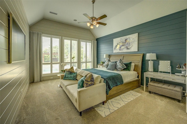 carpeted bedroom with wooden walls, a ceiling fan, and vaulted ceiling