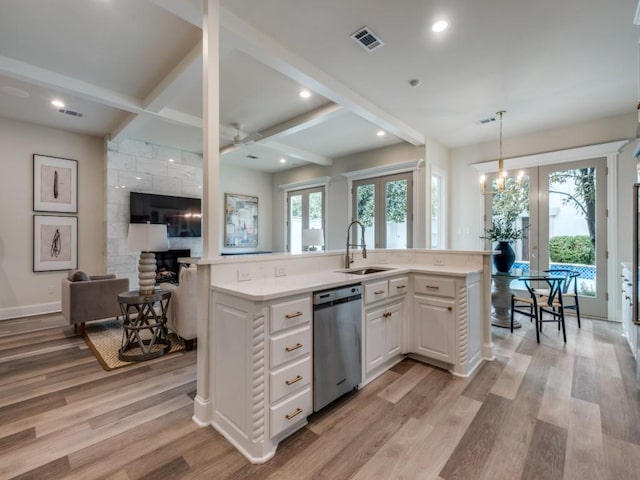kitchen featuring stainless steel dishwasher, light wood-style flooring, a sink, open floor plan, and french doors