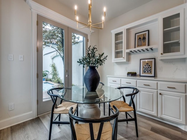 dining room with a notable chandelier, baseboards, french doors, and light wood-type flooring