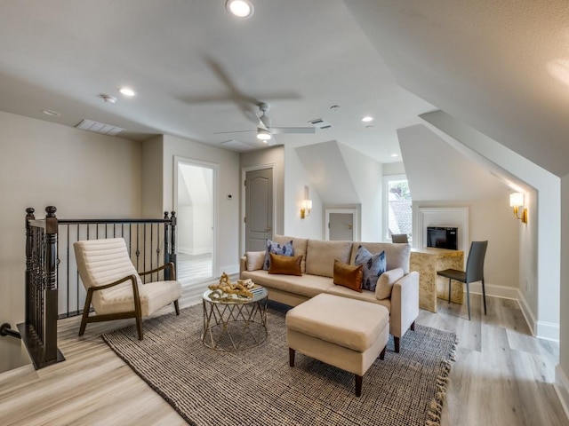 living room with light wood-style flooring, visible vents, ceiling fan, baseboards, and a glass covered fireplace