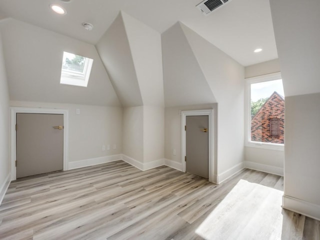 additional living space with visible vents, light wood-style floors, baseboards, recessed lighting, and lofted ceiling with skylight