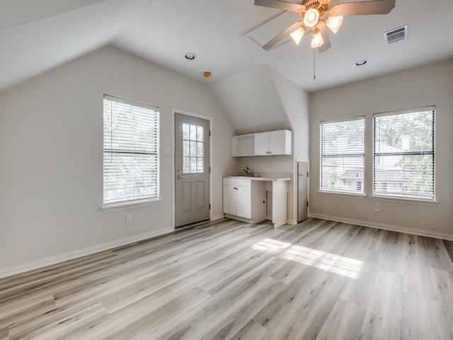 additional living space featuring a sink, visible vents, ceiling fan, light wood finished floors, and vaulted ceiling