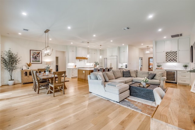 living room with recessed lighting, light wood finished floors, visible vents, and beverage cooler