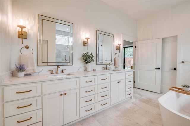 bathroom featuring a freestanding tub, a healthy amount of sunlight, and a sink