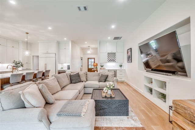living area with visible vents, recessed lighting, and light wood-style flooring