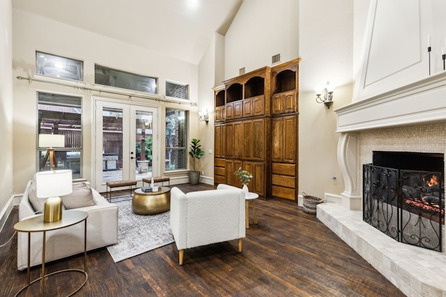 1233 Deer Lake Dr, Frisco, TX 75036 - living room featuring french doors, high vaulted ceiling, dark wood finished floors, visible vents, and a warm lit fireplace