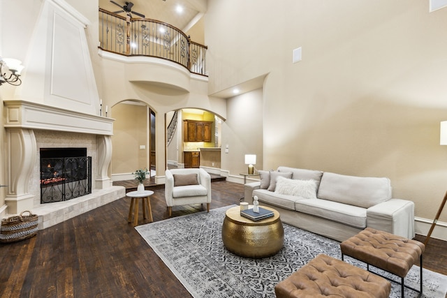 1233 Deer Lake Dr, Frisco, TX 75036 - living area featuring a fireplace, arched walkways, dark wood-style floors, a high ceiling, and baseboards
