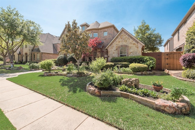 1233 Deer Lake Dr, Frisco, TX 75036 - view of front facade featuring stone siding, a front yard, fence, and a gate