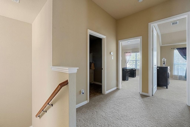 hall featuring an upstairs landing, carpet, visible vents, and baseboards