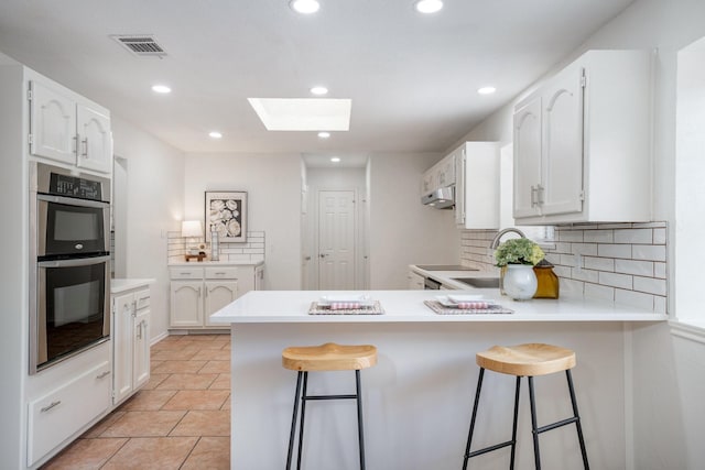 4703 El Brevo Ct, Arlington, TX 76017 - kitchen with visible vents, a skylight, a peninsula, and white cabinets