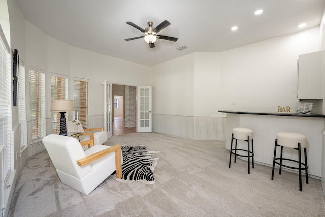 4703 El Brevo Ct, Arlington, TX 76017 - living area with light colored carpet, visible vents, ceiling fan, french doors, and wainscoting