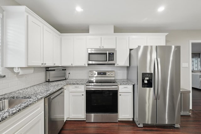kitchen featuring light stone counters, white cabinetry, stainless steel appliances, and tasteful backsplash