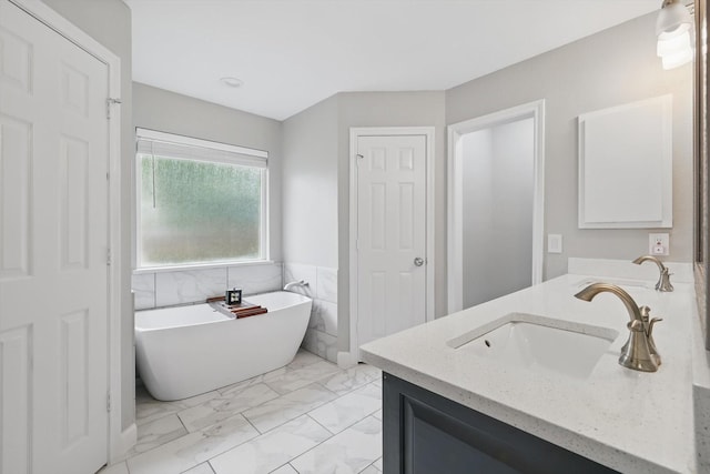 bathroom with a soaking tub, a sink, double vanity, marble finish floor, and wainscoting