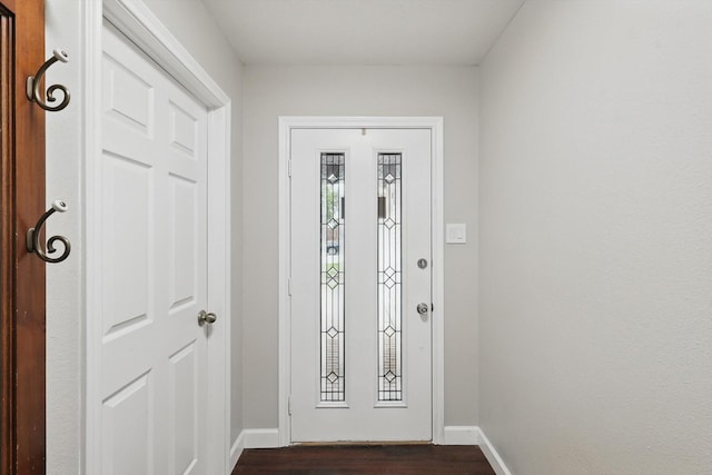 doorway with baseboards and dark wood-type flooring