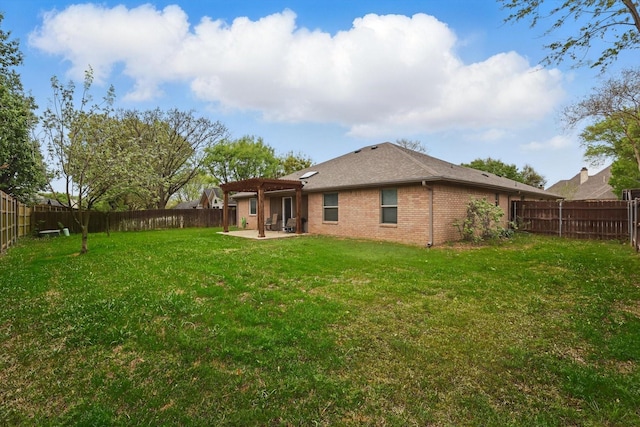 rear view of house featuring brick siding, a yard, a fenced backyard, and a patio area