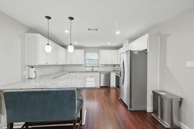 kitchen featuring visible vents, a peninsula, appliances with stainless steel finishes, and decorative backsplash