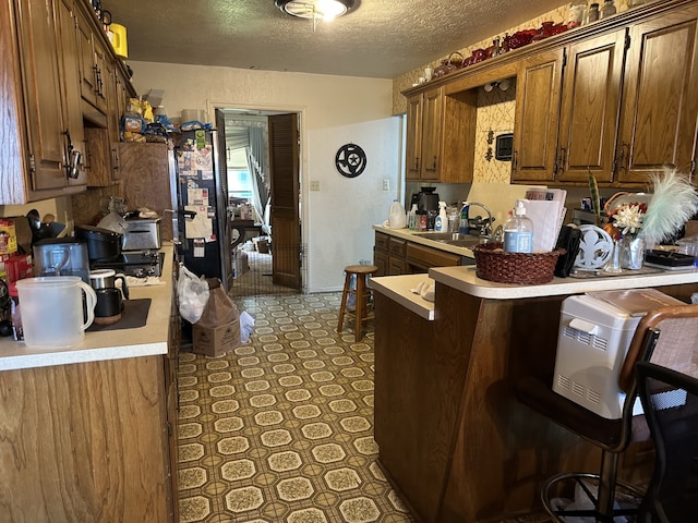 kitchen with light floors, a sink, a peninsula, and light countertops