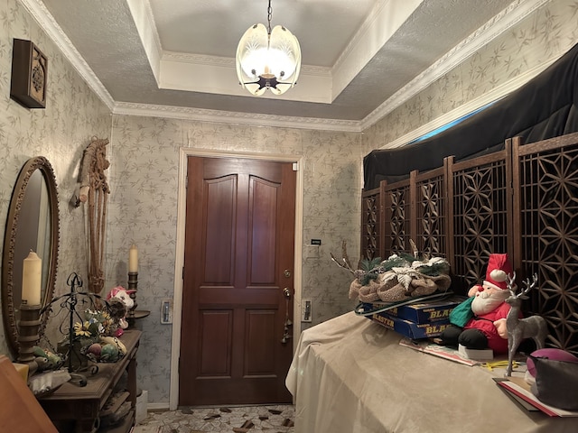 foyer entrance with an inviting chandelier, crown molding, and a tray ceiling