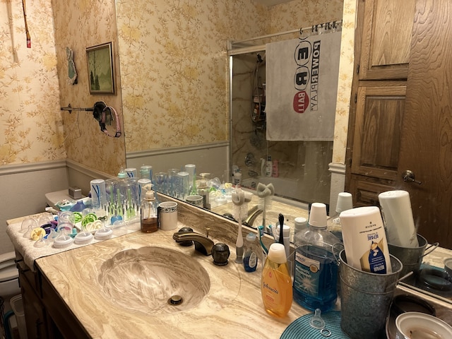 full bath featuring wallpapered walls, a wainscoted wall, and vanity