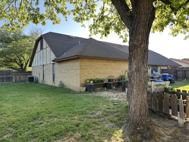 view of side of property featuring a fenced backyard, brick siding, roof with shingles, cooling unit, and a lawn