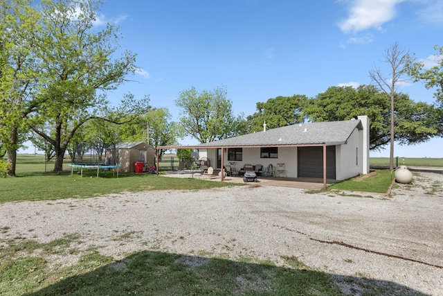 rear view of property with an outdoor structure, a yard, a storage shed, a garage, and dirt driveway