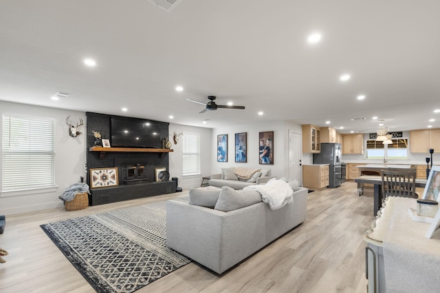 living area featuring baseboards, recessed lighting, light wood finished floors, a fireplace, and a ceiling fan