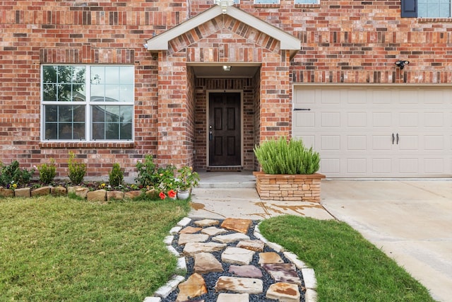 doorway to property with driveway, a yard, an attached garage, and brick siding