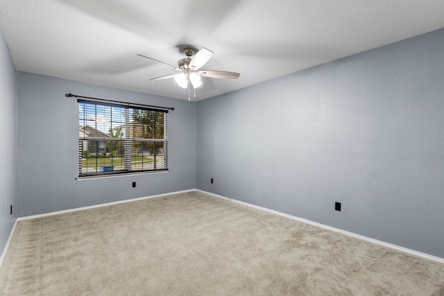 empty room featuring carpet, a ceiling fan, and baseboards