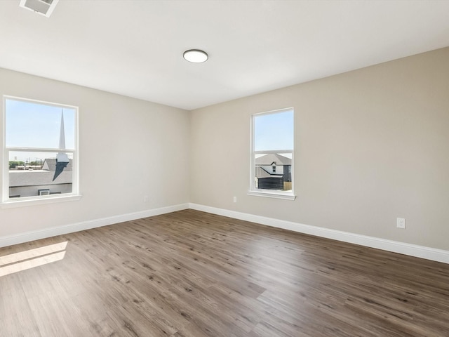 8008 W Elizabeth Ln, Fort Worth, TX 76116 - empty room featuring visible vents, baseboards, wood finished floors, and a healthy amount of sunlight