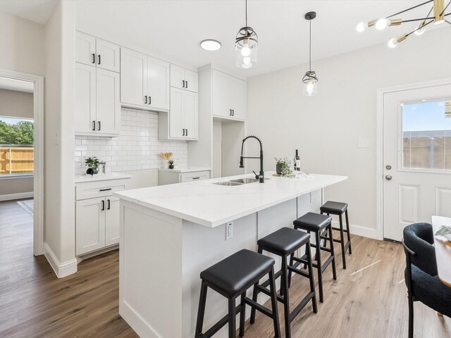 8008 W Elizabeth Ln, Fort Worth, TX 76116 - kitchen with a sink, backsplash, light wood-style flooring, baseboards, and white cabinets