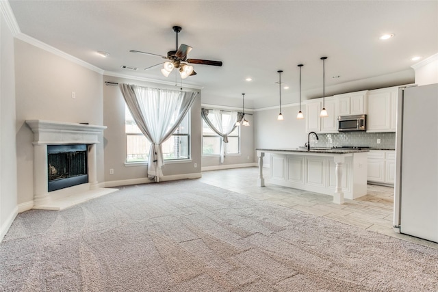 unfurnished living room with a sink, ceiling fan, visible vents, baseboards, and ornamental molding