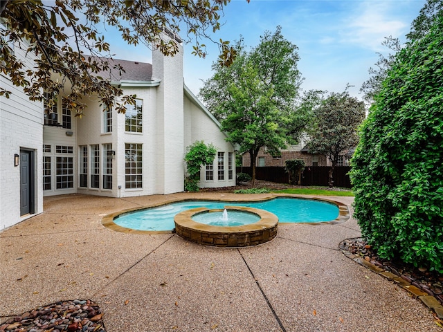view of pool with fence, a patio, a pool with connected hot tub, and french doors