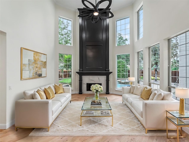 living area with baseboards, a towering ceiling, wood finished floors, and a premium fireplace