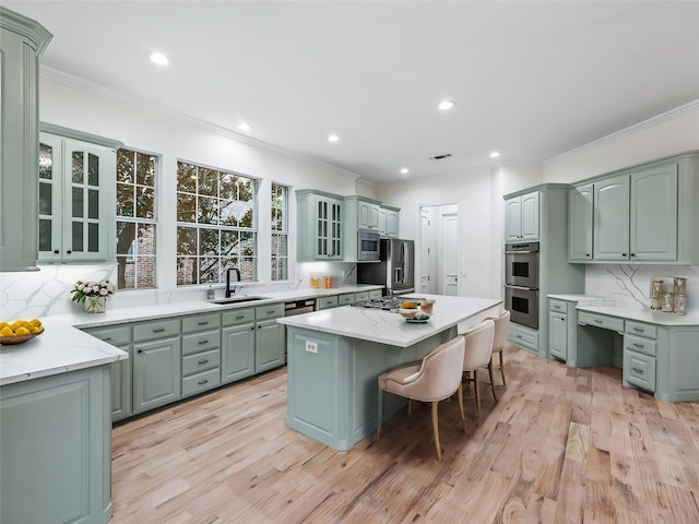 kitchen with a sink, appliances with stainless steel finishes, tasteful backsplash, and a kitchen island