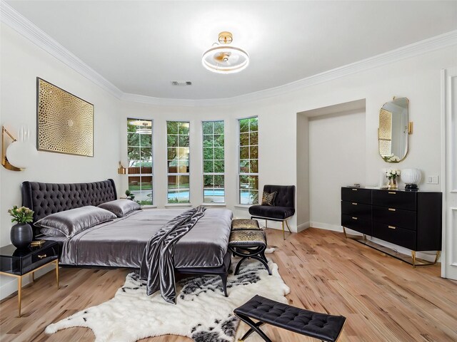 bedroom with crown molding, light wood-style flooring, baseboards, and visible vents