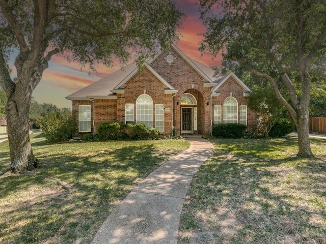 single story home featuring fence, brick siding, and a front lawn