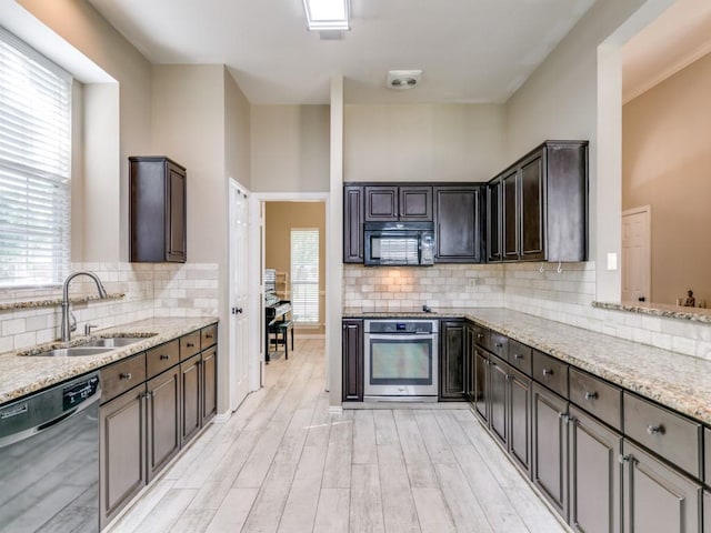 kitchen with oven, dishwasher, light wood finished floors, a sink, and black microwave