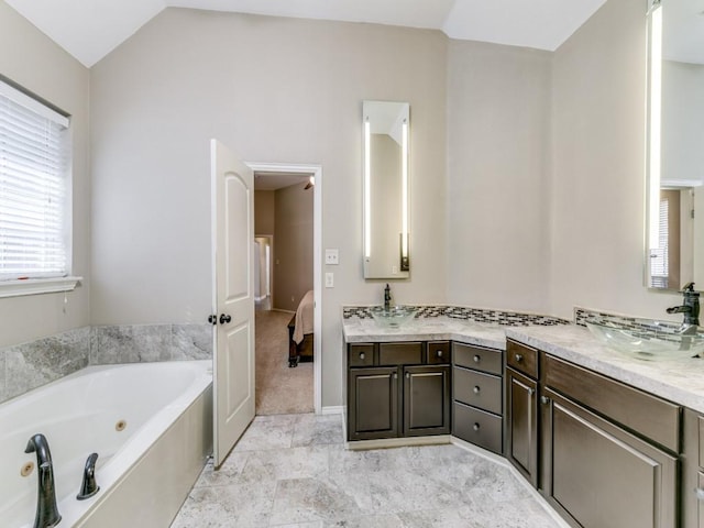 ensuite bathroom with a tub with jets, vanity, ensuite bath, and vaulted ceiling