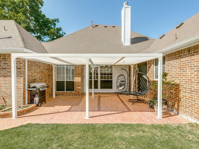 rear view of house with a chimney, a shingled roof, a patio area, and brick siding