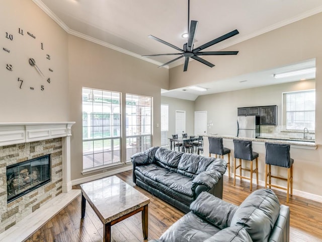 living room with light wood finished floors, a healthy amount of sunlight, a ceiling fan, and ornamental molding