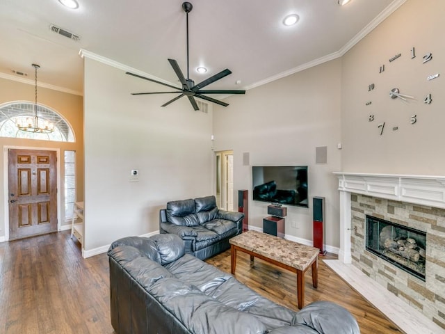living room featuring visible vents, baseboards, ornamental molding, a high ceiling, and ceiling fan with notable chandelier