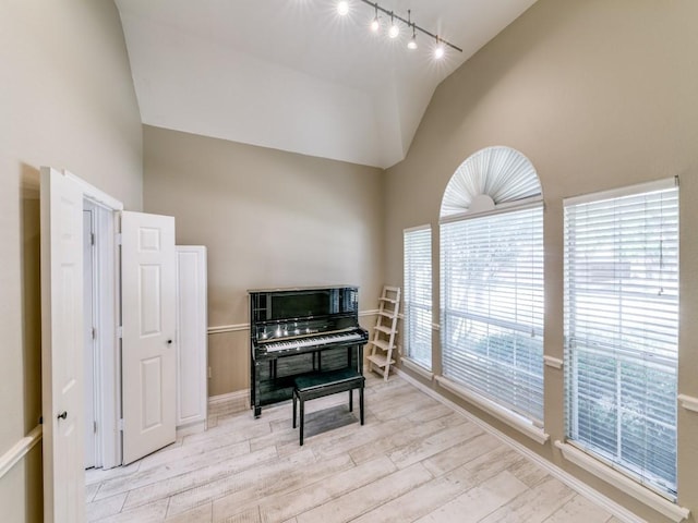 sitting room featuring track lighting, light wood-type flooring, and high vaulted ceiling
