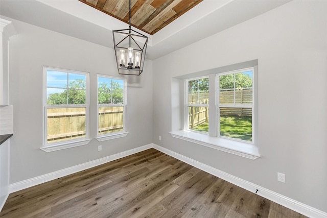 unfurnished dining area with a chandelier, wooden ceiling, a healthy amount of sunlight, and baseboards