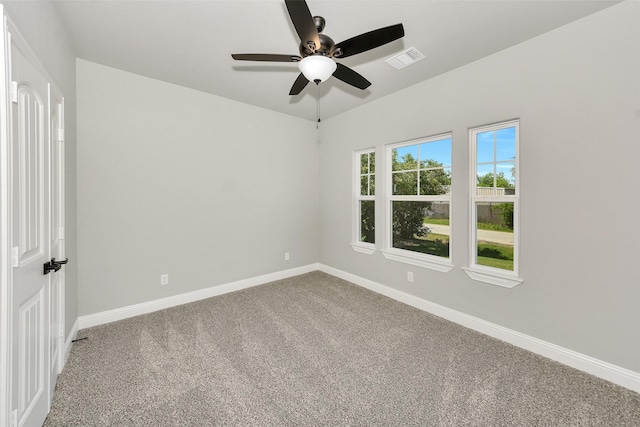 carpeted empty room featuring a ceiling fan, visible vents, and baseboards