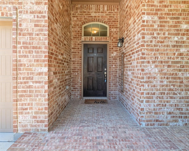 view of exterior entry featuring brick siding