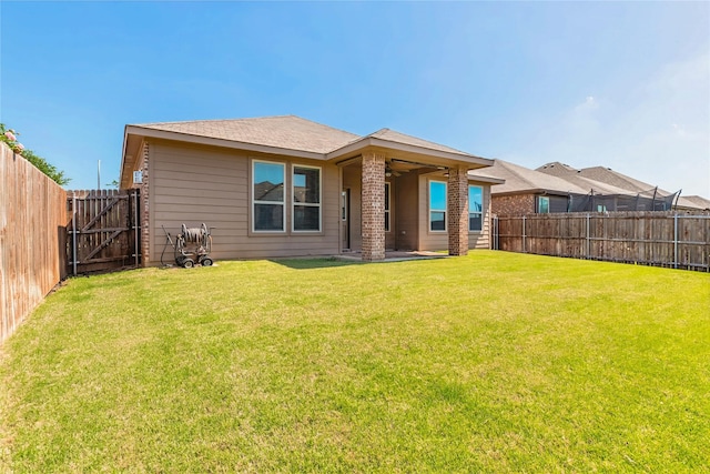 rear view of house featuring a patio area, a yard, ceiling fan, a fenced backyard, and a gate