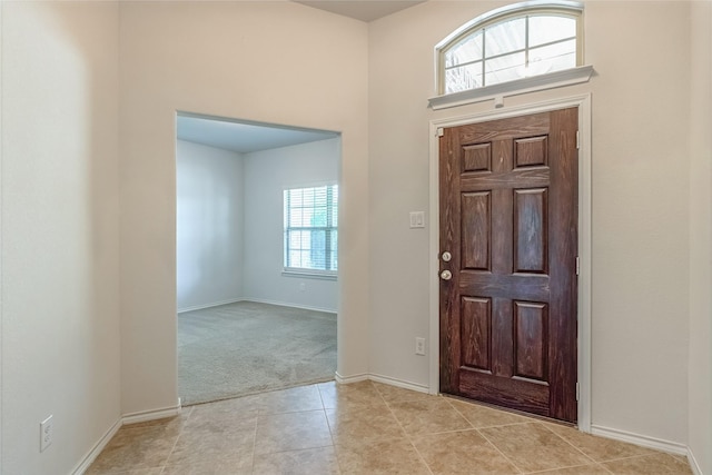 foyer entrance with light tile patterned floors, baseboards, and light carpet