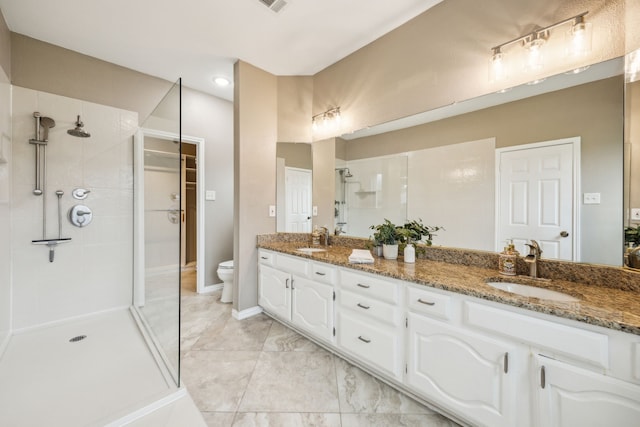 full bathroom featuring double vanity, toilet, a stall shower, and a sink