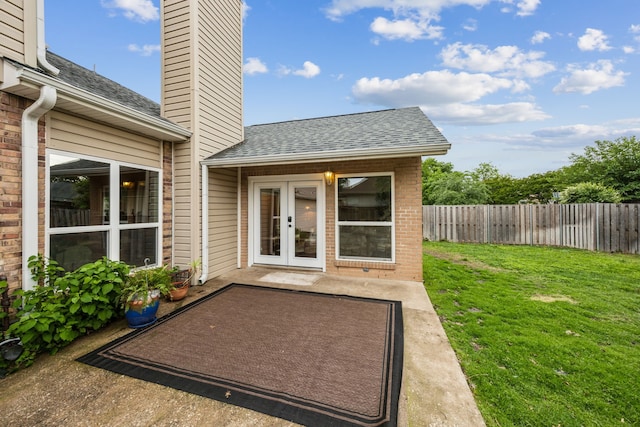 exterior space featuring a yard, a chimney, brick siding, roof with shingles, and fence